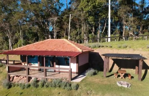 Vila rústica com telhado vermelho em Paraíso nas Montanhas, refúgio nas montanhas de Campos do Jordão com deck de madeira e floresta