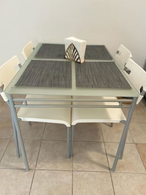 Zona pranzo moderna dell'appartamento Newhouse a Bari con tavolo in vetro, sedie imbottite e centrotavola decorativo