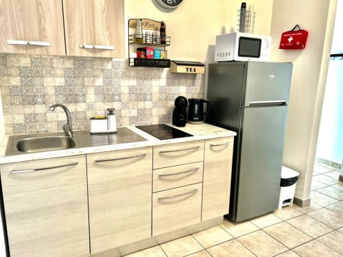 Cucina moderna dell'appartamento Newhouse a Bari con mobili in legno chiaro, elettrodomestici in acciaio inossidabile e rivestimento decorativo