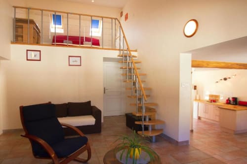 Séjour loft contemporain au Gîte La Grange à Neuf-Brisach avec mezzanine, escalier bois et mobilier design.