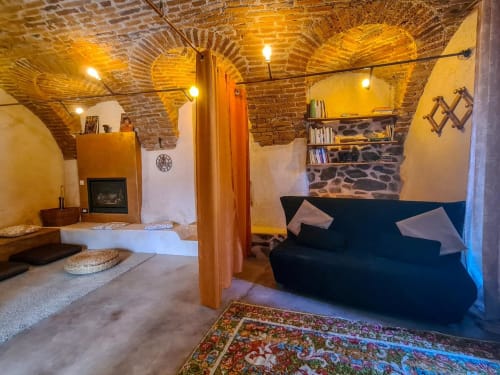 Suite CasaRosada B&B a Vidracco con soffitto in laterizio a vista, camino, letto, divano nero e tappeto colorato
