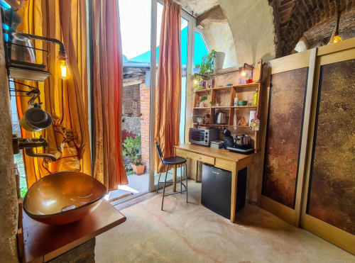 Rustic kitchen and workspace at CasaRosada B&B in Vidracco with copper sink, wooden desk, and terracotta tones.