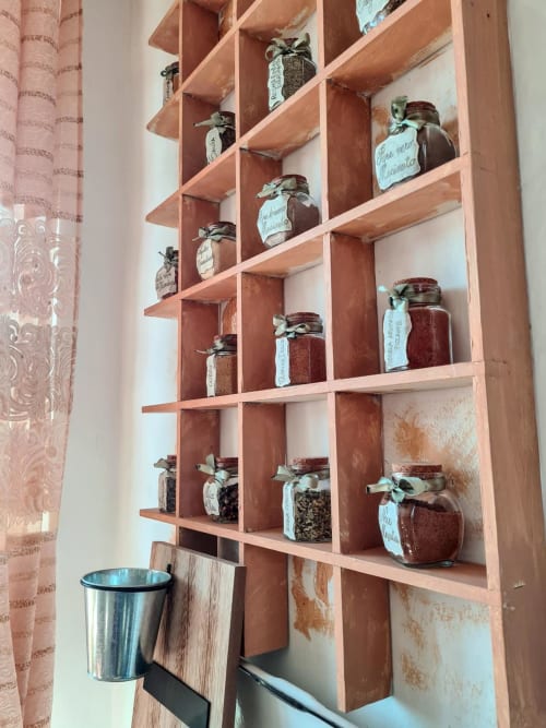Rustic wooden shelving unit at CasaRosada displaying preserved jars with handwritten labels in Vidracco