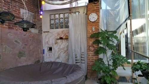 CasaRosada BnB bedroom in Vidracco featuring exposed brick, plants, cozy bed, and modern clock
