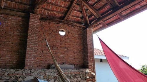 Rustic brick courtyard at CasaRosada B&B in Vidracco, Italy, with traditional wooden roof beams and red fabric awning