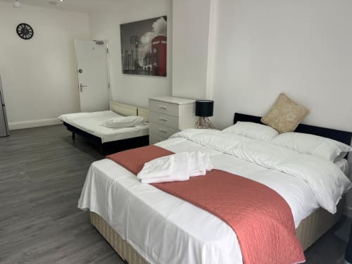 Twin bedroom at Starlet Property London hotel with white bedding, red bed runner, and ensuite bathroom