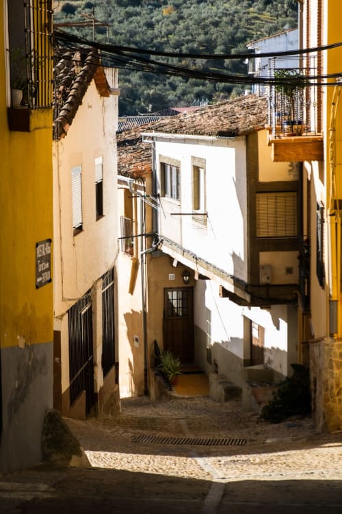 Encantador callejón empedrado en Mérida con edificios coloniales amarillos y colinas verdes de fondo