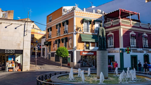 Coloridas casas coloniales y fuente en la plaza histórica de Mérida, con arquitectura naranja, roja y amarilla