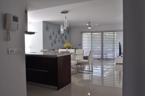Cocina moderna de concepto abierto y comedor en Mareazul Resort Frente al Mar con isla negra, iluminación colgante y vista al océano
