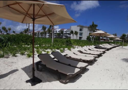 Tumbonas y sombrillas en la playa del Resort Mareazul en Playa del Carmen, con vistas a arena y palmeras