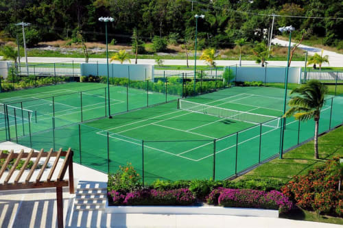 Canchas de tenis profesionales en Mareazul Beachfront Resort, Playa del Carmen, con superficies verdes, líneas blancas y entorno tropical
