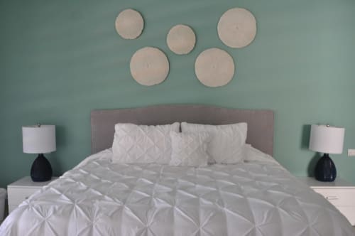 Habitación moderna en Mareazul Resort Frente al Mar con paredes verde menta, cabecera gris, ropa de cama blanca y arte circular en la pared