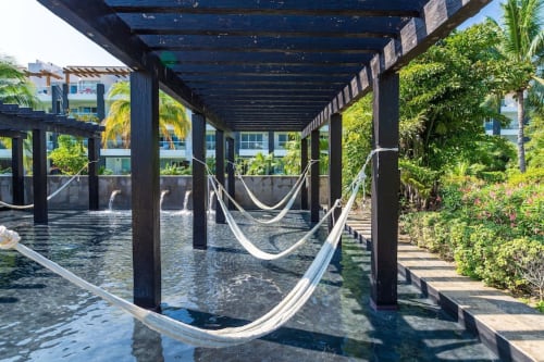 Hamacas frente al mar bajo pérgola en Mareazul Resort de Playa del Carmen, con jardines tropicales y vistas al océano.