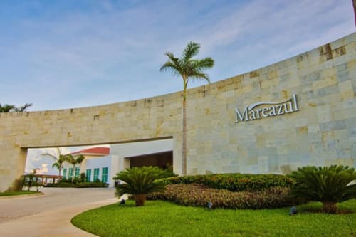 Entrada del Resort Mareazul frente al mar en Playa del Carmen con fachada de piedra moderna, palmeras y jardines bien cuidados