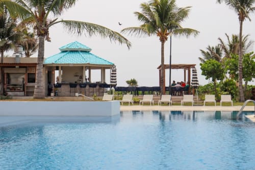 Área de piscina del Resort Mareazul frente al mar con cabaña turquesa, tumbonas y palmeras en Playa del Carmen