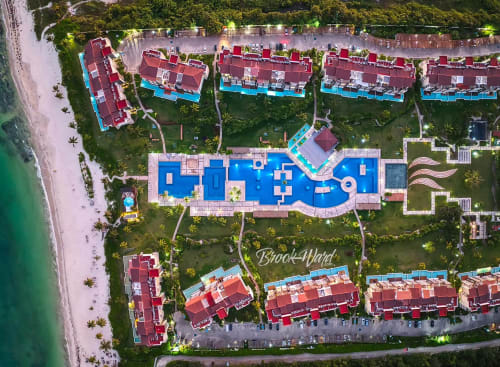 Vista aérea del Mareazul Beachfront Resort con villas de tejado rojo, piscinas azules y playa caribeña en Playa del Carmen