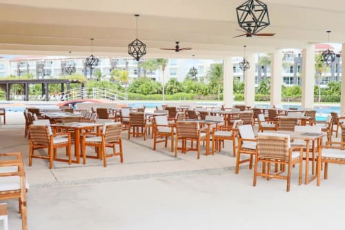 Área de comedor cubierta frente al mar en Mareazul Resort, Playa del Carmen, con sillas de madera, lámparas colgantes geométricas y piscina