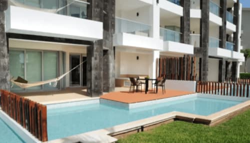 Área de piscina del Resort Mareazul frente al mar en Playa del Carmen con arquitectura moderna, espacios de descanso y terraza.