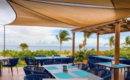 Terraza del Resort Mareazul frente al mar con mesas turquesas, sillas azul marino y vistas al océano en Playa del Carmen