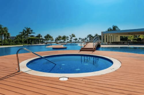 Piscina circular del Mareazul Beachfront Resort con agua azul, terraza de madera y palmeras en Playa del Carmen