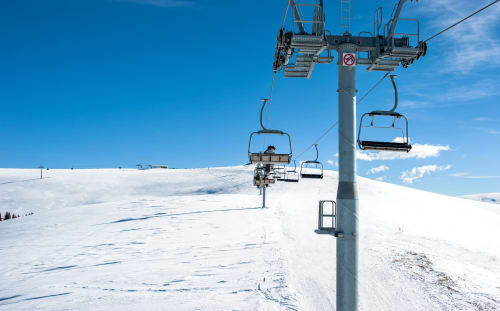 Ski lift at Résidence Le Pacha in Courchevel with snow-covered slopes and blue sky
