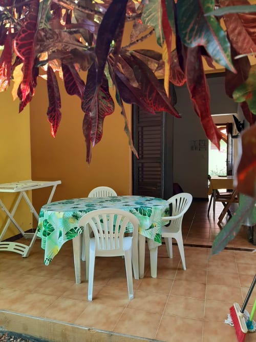 Outdoor dining area at Mon Refuge hotel in Martinique with tropical plants, white chairs, and colorful tablecloth