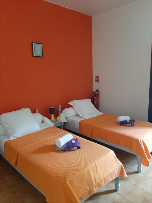 Twin beds with orange blankets in bright, modern Serenity apartment at Residence de Vacances Mon Refuge, Martinique