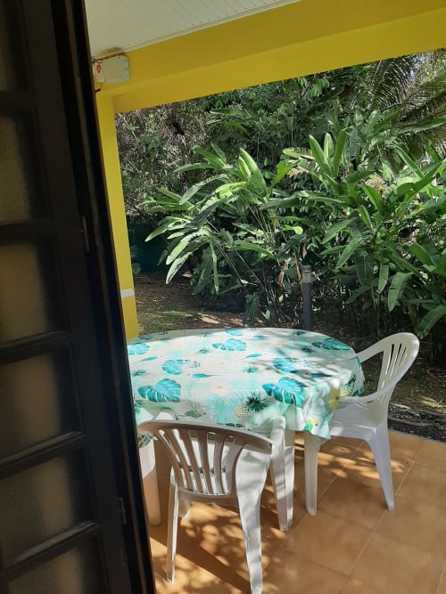 Tropical garden terrace at Mon Refuge with dining table, white chairs, and lush vegetation in Les Anses d'Arlet