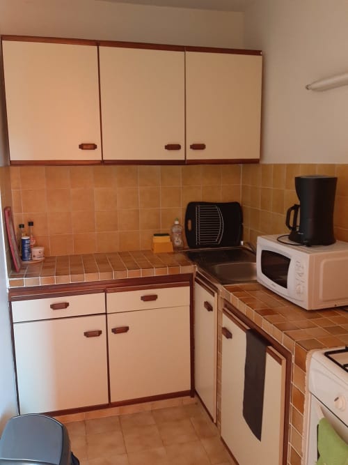 Kitchen area of apartment at Residence de Vacances Mon Refuge in Martinique with beige cabinets, orange tile backsplash,