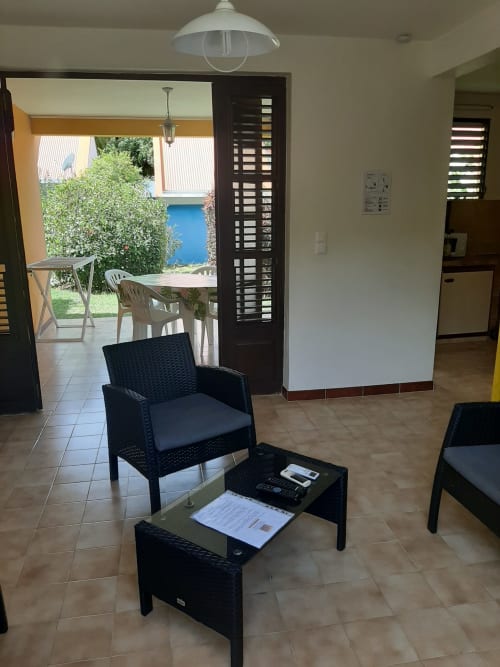 Espace lounge moderne avec fauteuil et table en rotin noir, vue sur le jardin de la location Mon Refuge en Martinique