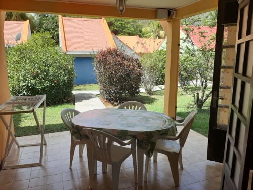 Patio ombragé avec table et chaises de salle à manger donnant sur jardin tropical à Mon Refuge, Les Anses d'Arlet