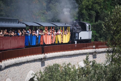 Train à vapeur aux couleurs vives avec passagers près du Mas de Trépeloup à Alès, France