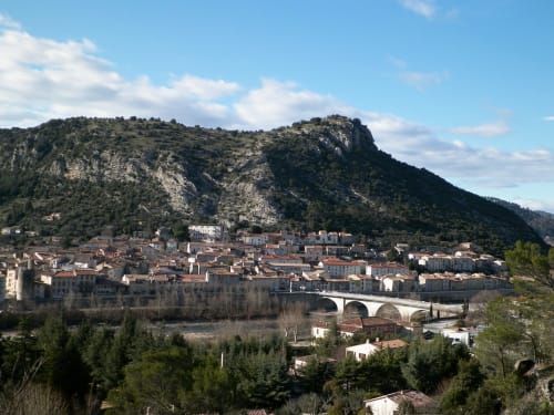 Médiéval village d'Alès avec rivière, pont de pierre et collines boisées sous ciel bleu