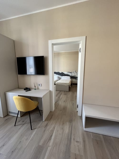 Camera moderna a Breccia nel Mare con scrivania, sedia gialla, TV a schermo piatto e accesso alla camera da letto a Marina di Carrara