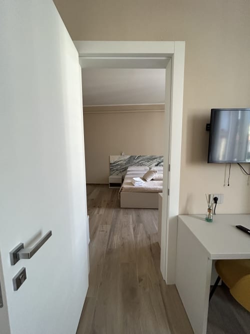 Camera moderna dell'hotel Breccia nel Mare con letto, scrivania, TV e pavimenti in legno a Marina di Carrara