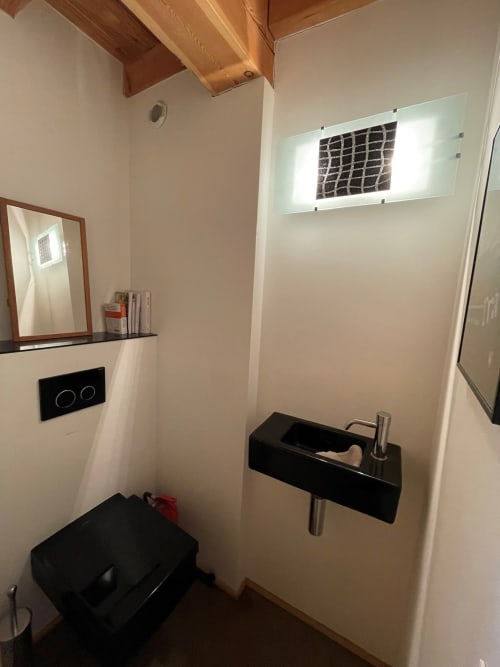 Salle de bain moderne de l'appartement Chalet Du Sarrasin à Tignes, avec lavabo noir, miroir illuminé et poutres en bois