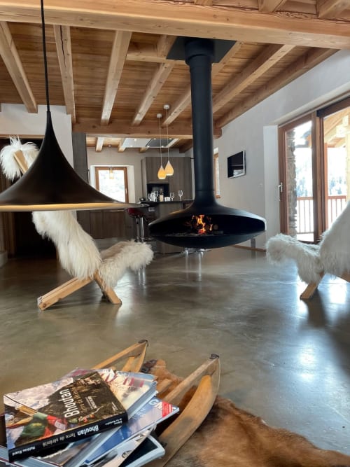 Intérieur chaleureux du Chalet Du Sarrasin à Tignes : foyer suspendu, poutres bois et sièges en fourrure blanche