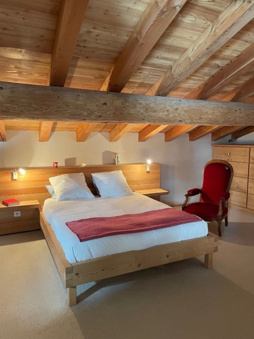 Chambre rustique au Chalet Du Sarrasin à Tignes avec poutres apparentes, lit en bois et fauteuil rouge
