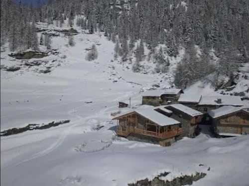 Le refuge alpin Chalet Du Sarrasin à Tignes enneigé, entouré de forêts de conifères et d'un lac gelé