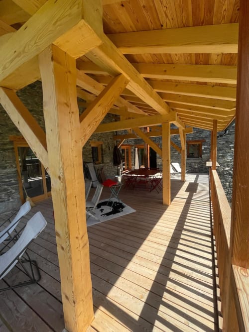 Pergola et terrasse en bois du Chalet Du Sarrasin à Tignes avec bâtiment en pierre et vue sur les montagnes