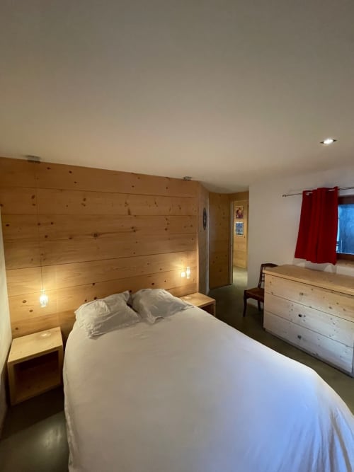 Chambre douillette du Chalet Du Sarrasin à Tignes avec tête de lit en bois, literie blanche et mobilier alpin