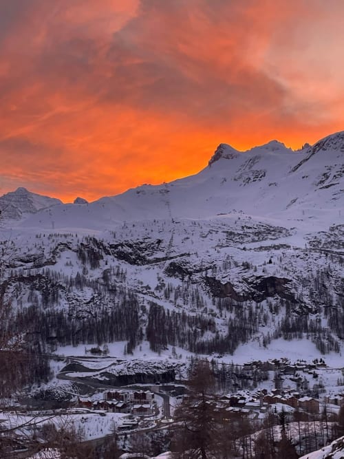 Montagnes alpines enneigées au coucher de soleil sur la station de ski de Tignes avec un refuge montagnard niché dans la vallée