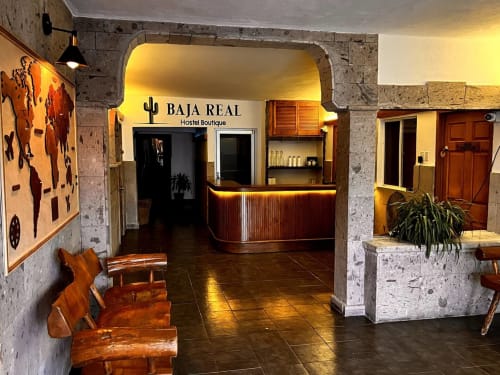 Área de recepción del Baja Real Hostel Boutique en La Paz con iluminación cálida, muebles de madera y arco de piedra