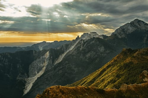 Paesaggio montano spettacolare con raggi dorati del tramonto e vette boscose vicino a Marina di Carrara