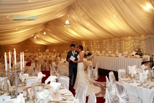 Bride and groom in elegant wedding reception tent at Sliabh Beagh Hotel, Monaghan with gold draping and candle centerpieces