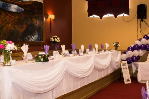 Elegant wedding reception setup at Sliabh Beagh Hotel in Monaghan with draped tables, purple balloons, and floral
