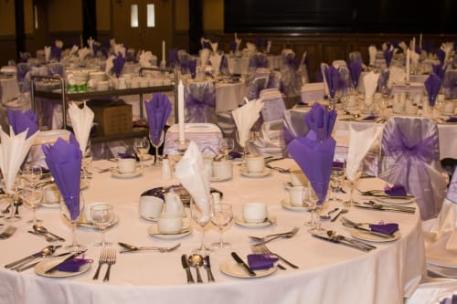 Elegant banquet hall at Sliabh Beagh Hotel with white linens, purple napkins, and formal place settings.