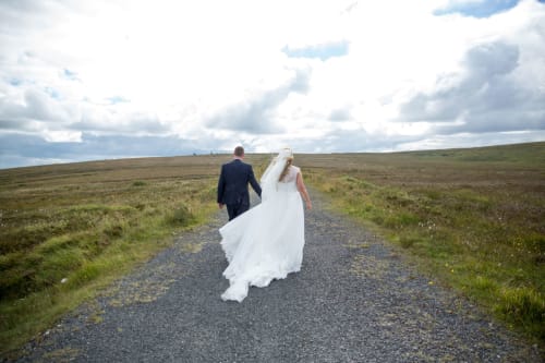 Bride and groom walking on rural countryside road near Sliabh Beagh Hotel in Monaghan, Ireland
