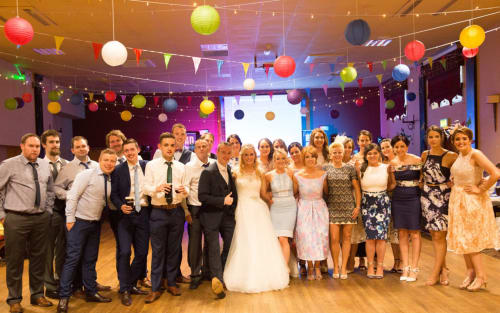 Wedding party group photo at Sliabh Beagh Hotel, Monaghan with colorful hanging decorations and string lights in venue.