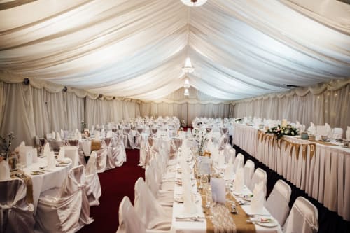 Elegant wedding reception tent at Sliabh Beagh Hotel in Monaghan with white draped tables and champagne-colored chair covers